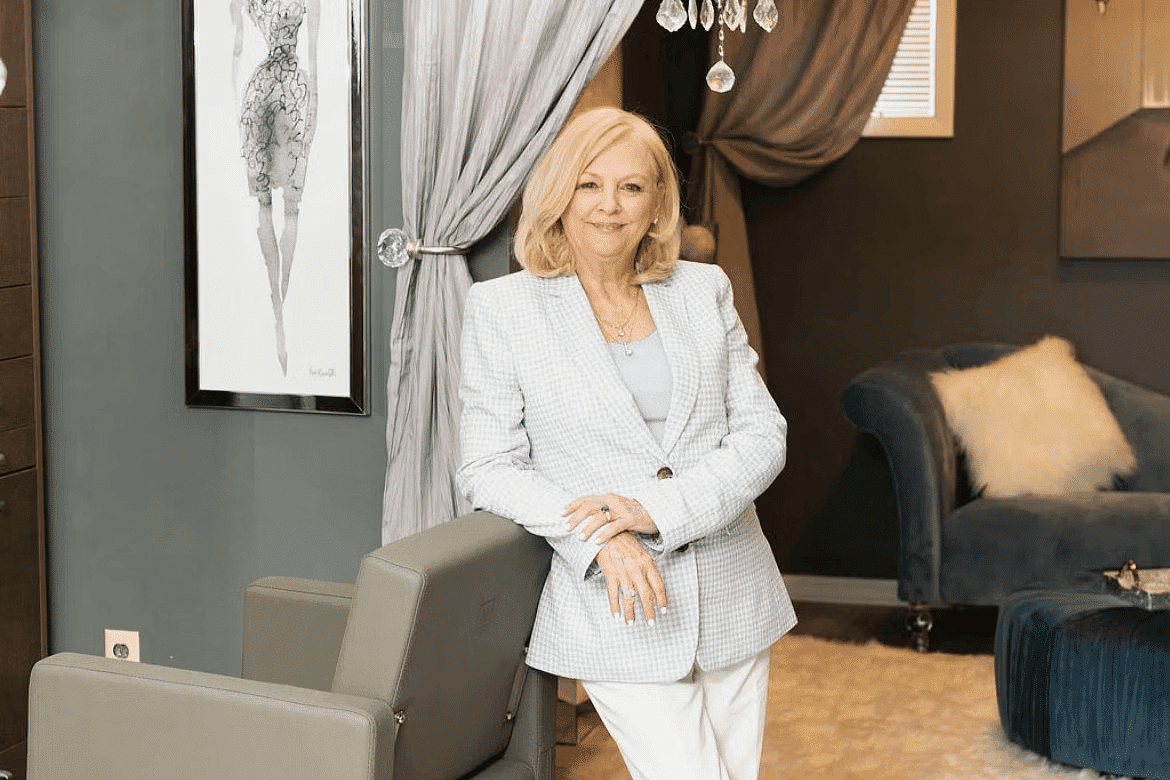 Woman in a stylish salon, standing by a modern hairdresser's chair with a chandelier above.