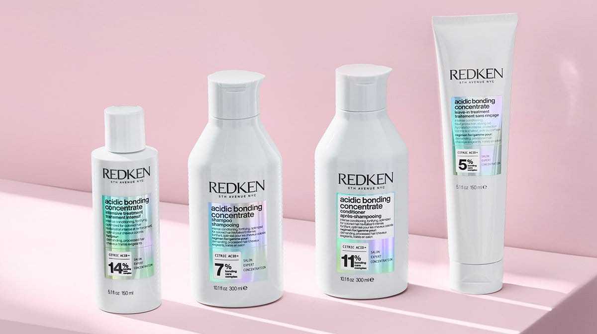 Four Redken acidic bonding concentrate hair care products against a pink background.